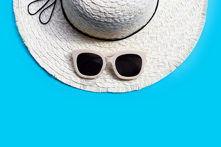 带夏季帽子的太阳镜在蓝色背景上。