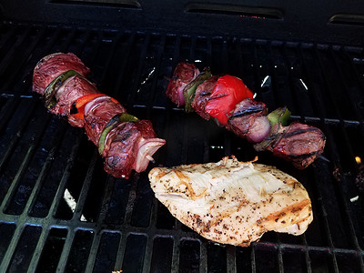 牛肉串配洋葱和辣椒，放在烤架上的棍子上，配上鸡肉