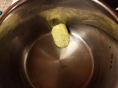炉子上金属锅中的冷冻绿色香蒜酱