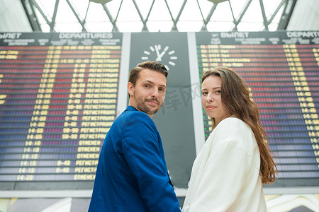 年轻夫妇在国际机场查看航班信息板