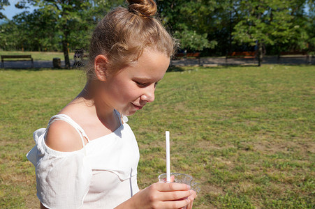 夏季公园里女孩用吸管喝果汁