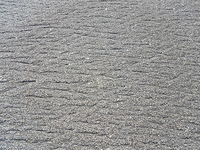 线条沙滩摄影照片_沙滩上的灰色沙子或土壤，上面有鹅卵石