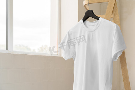 纯白色模板摄影照片_纯白色棉质 T 恤挂在衣架上，适合您的设计