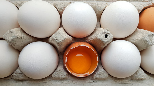 破了的鸡蛋摄影照片_一个鸡蛋在其他鸡蛋中破了一半。