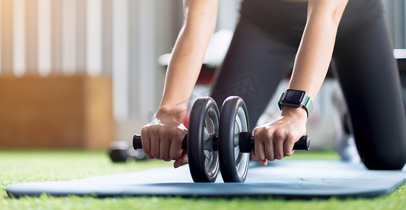 手部妇女在健身房里用腹轮进行锻炼。