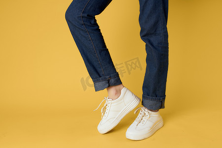 女式腿牛仔裤白色运动鞋时尚街头风格黄色背景
