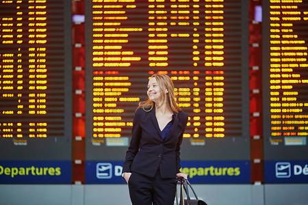 国际机场的年轻女性看着航班信息板，检查她的航班