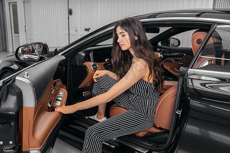 车辆启动摄影照片_年轻的亚洲女性在启动引擎前坐在车库的豪华车里
