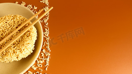 用筷子在盘子上呈典型圆形的干方便面。