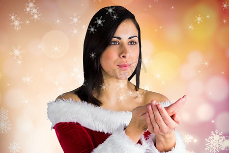 穿着圣诞老人服装的女人在数字生成的背景下吹雪花