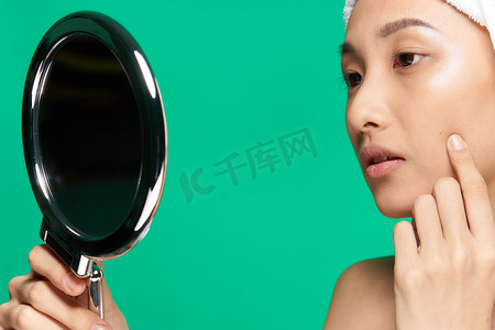 漂亮女人手上的镜子干净的皮肤脸特写绿色背景
