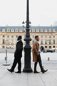 服装要求摄影照片_非裔美国人和白人男子站在城市的路灯附近。