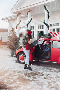 年轻夫妇为他们的家人购买圣诞礼物，并用一辆红色汽车将他们带回家