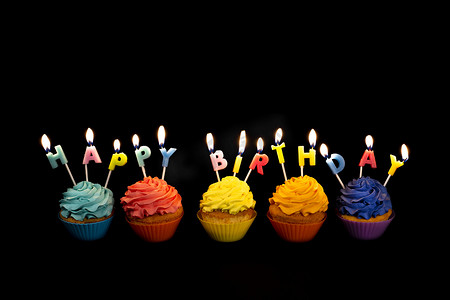 带有彩色纸杯蛋糕和蜡烛的横幅，拼写着黑色背景中突显的生日快乐