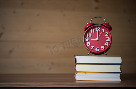 早上 9 点闹钟在木桌上的书堆上。