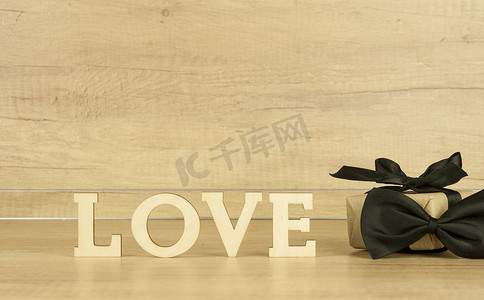 木桌上有蝴蝶领带和礼品盒的木字“LOVE”