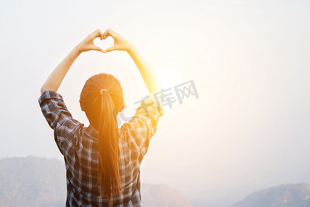 下期更精彩摄影照片_我喜欢旅行概念：自由旅行的女人用心形的手站着，在日出时享受美妙的大自然，晨光效果