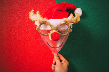可爱的圣诞鹿摄影照片_手拿着装饰着驯鹿和的圣诞眼镜