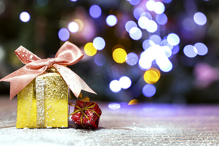 圣诞快乐，新年，金盒里的礼物，雪地里有粉色蝴蝶结，圣诞树背景有复制空间，假日，现在的概念