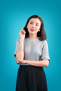 双旦狂欢海报摄影照片_微笑可爱的亚洲女人穿着蓝色的海报风格连衣裙。