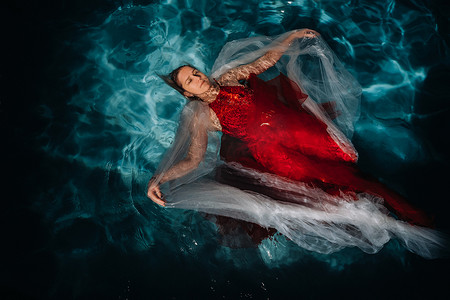 一个穿红裙子的女孩漂浮在水面上。一个单身女人的水上之旅