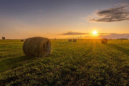 夏日田野摄影照片_夏日傍晚夕阳下的干草堆田野。