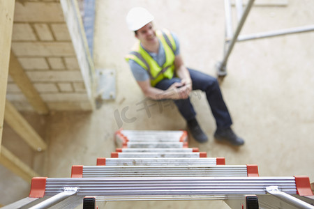 建筑工人劳动者摄影照片_建筑工人从梯子上掉下来伤腿