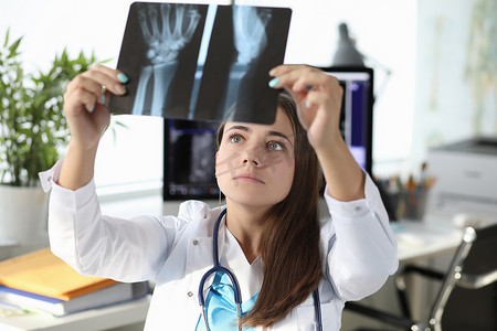 手部x光片摄影照片_女医生在诊所办公室看手部 X 光片