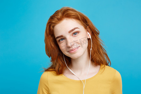 听收音机摄影照片_生活方式概念 — 欢快快乐的姜红头发女孩的肖像喜欢戴着耳机听音乐，对着镜头欢快地微笑。