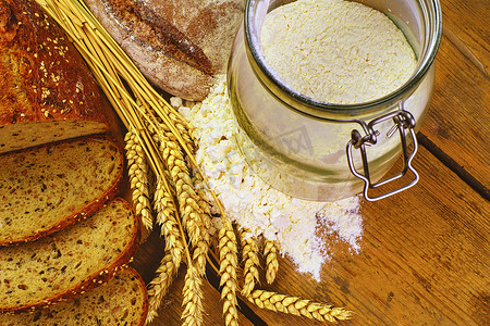面包、面包片、小麦粉和木头背景上的谷穗。