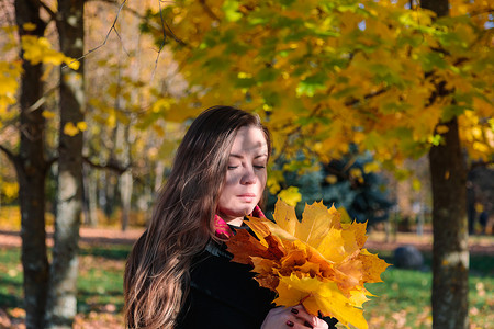 一个长头发的女人看着秋天公园里的黄叶。