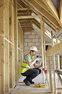 建筑工人在房屋建造中使用钻孔机
