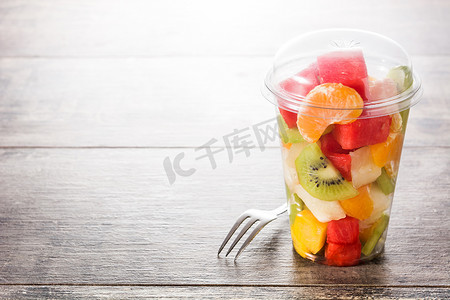 木桌上塑料杯中的鲜切水果