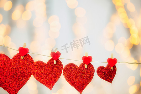 红色贺卡摄影照片_快乐的情人节背景，红心挂着衣夹，绳子上有散景背景、浪漫设计、贺卡或复印空间