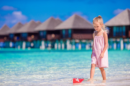 可爱的小女孩在绿松石海里玩折纸船