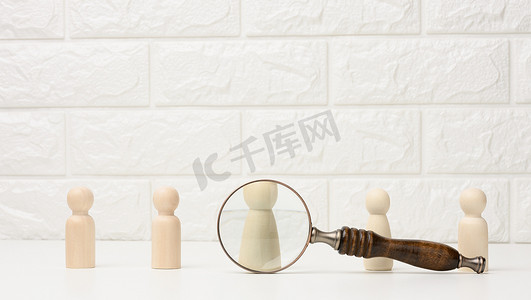 公司邀请函的摄影照片_男人的木制人物站在白色背景和放大镜上。