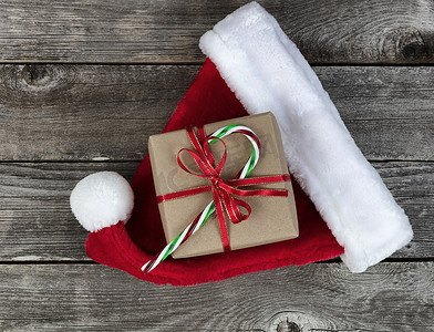 礼盒绿色摄影照片_褪色木板上的圣诞老人帽和礼盒，以庆祝圣诞快乐或新年快乐