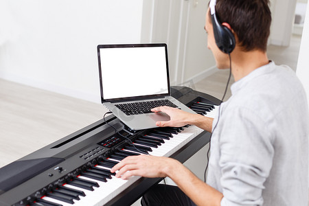 男性作曲家手使用电脑、midi 键盘和工作室设备在办公桌上制作歌曲和声音设计，用于后期制作或电影乐谱