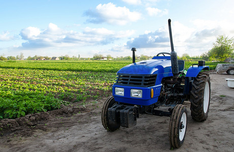 农业补贴摄影照片_没有司机的蓝色拖拉机在农田附近。
