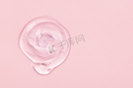 在粉红色背景上隔离的透明凝胶滴或涂片。