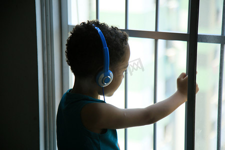 小孩音乐摄影照片_窗边戴耳机的小孩
