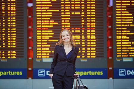 国际机场航站楼提着手提行李的女人，看着信息板