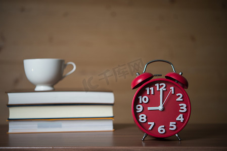 木头堆摄影照片_早上 9 点的闹钟和一堆书，木头上放着一杯咖啡