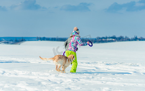 带着狗在雪地里奔跑的女孩