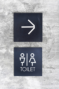卫生间门摄影照片_混凝土墙风格精品店上的男女通用卫生间或卫生间和箭头标志