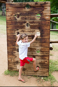 攀岩男孩摄影照片_男孩在公园的游乐场上攀爬