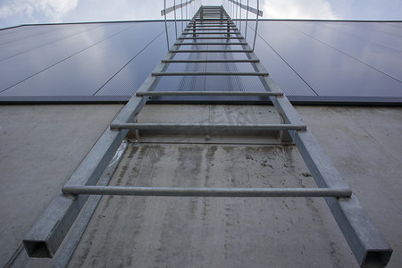 防火摄影照片_工业建筑上方的防火梯，底视图。