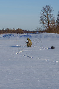 冰钻摄影照片_冬日在冰上钓鱼的钓鱼者