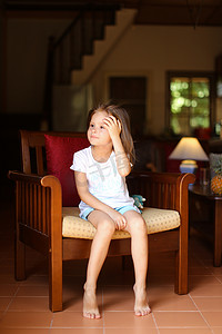 美国小女孩坐在客厅的木椅上。