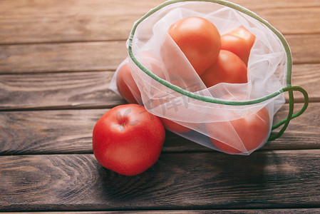 水果新鲜不新鲜摄影照片_装有西红柿的可重复使用的网眼袋。